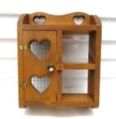 a small wooden shelf with two hearts on the front and one in the back, hanging from a wall