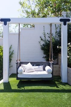 a white swing bed sitting on top of a lush green field