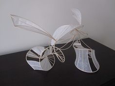 two white vases sitting on top of a black table next to each other and one is made out of paper