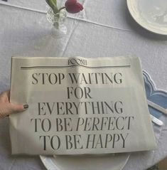 a person holding up a newspaper that reads stop waiting for everything to be perfect to be happy