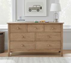 a wooden dresser sitting next to a window in a room with a lamp on top of it