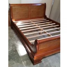 a wooden bed frame with rattan headboard and foot board on the bottom end