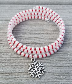 a red and white beaded bracelet with a silver snowflake charm on it