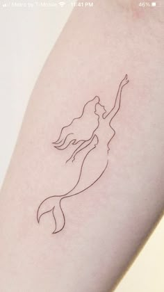 a woman's arm with a line drawing of a mermaid on the back of it