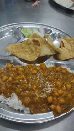 a silver plate topped with rice and beans next to tortilla chips on top of a table