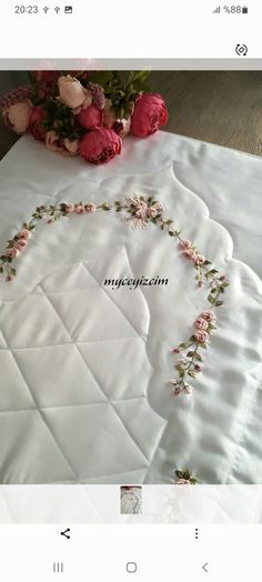 a white table cloth with pink flowers on it and a bouquet of roses in the middle