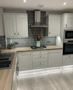 a kitchen with white cabinets and gray tile backsplashes, wood counter tops