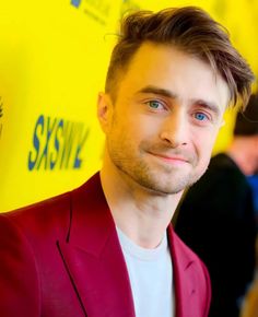 a man in a red suit and white shirt smiling at the camera with his eyes wide open