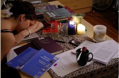 a woman sitting at a table with several books and candles on top of her desk