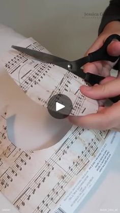 someone cutting sheet music paper with scissors