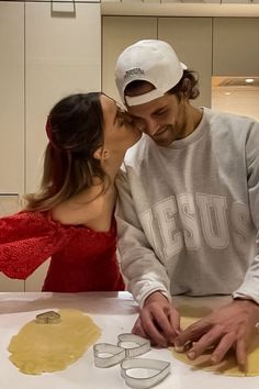 a man and woman are kissing in front of some cookie cutters