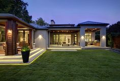 a modern house with lights on the front lawn and steps leading up to it's entrance