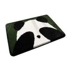 a black and white panda bear rug on top of a green area rug with an animal face