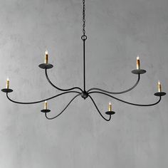 a black chandelier with five lit candles hanging from it's center point