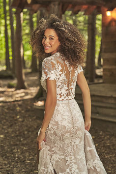 a woman in a wedding dress walking through the woods