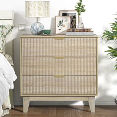 a bedroom scene with focus on the chest of drawers and plants in vases next to it