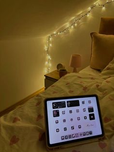 an electronic device sitting on top of a bed next to a night stand with lights