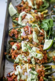 several stuffed peppers with sauce and toppings on a baking sheet, ready to be eaten