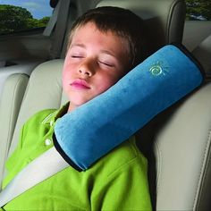 a young boy sleeping in the back seat of a car with his head on a pillow