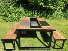 a wooden table with two laptops on it in the middle of some green grass