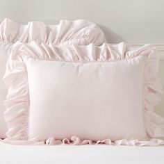 two pink pillows with ruffled edges on a bed