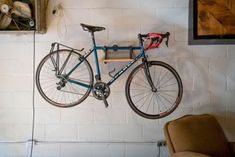 a bike hanging on the wall next to a chair