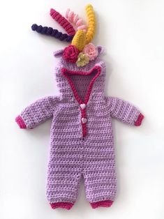 a crocheted baby's outfit with flowers on the head and hood is laying down