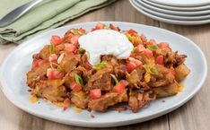 a white plate topped with taco meat and sour cream on top of a wooden table