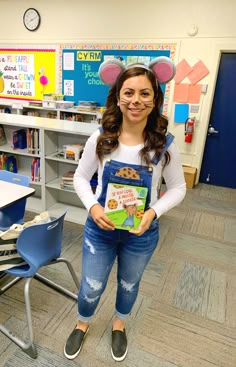 a girl is holding a book in front of her face and smiling at the camera