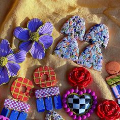 several decorated cookies sitting on top of a yellow towel next to purple flowers and hearts