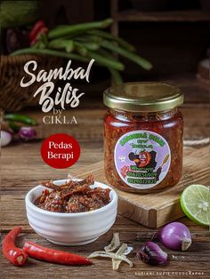 a jar of pickled peppers next to a bowl of chili paste and limes