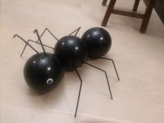 three black balls with sticks sticking out of them sitting on the floor next to each other