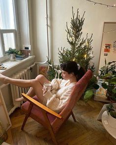 a woman sitting in a chair with a cat on her lap next to a christmas tree