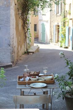 a table with food and wine on it in the middle of an alleyway between two buildings