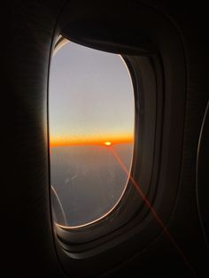 an airplane window with the sun setting in the sky as seen from it's seat