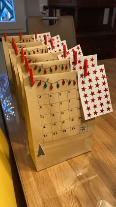 a wooden table topped with brown paper bags filled with calendars and christmas lights on them