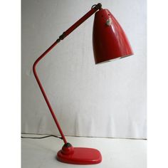 a red desk lamp sitting on top of a white table