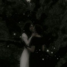 two people standing in front of a tree with stars on the branches and one person kissing the other