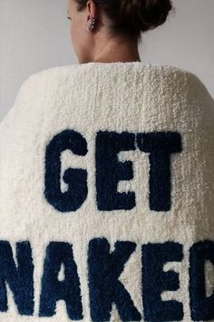 a woman wearing a white and blue sweater with the words get naked written on it