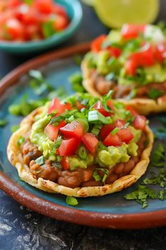 two tacos with guacamole and tomatoes on top are sitting on a blue plate