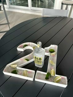 a table that has a bottle on it and some cups in front of the letters