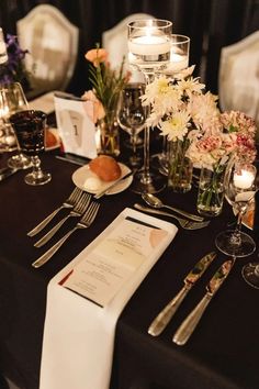 the table is set with silverware, flowers and menu cards for guests to eat