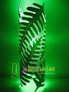 an illuminated vase with a green light in the background and a fern leaf on it