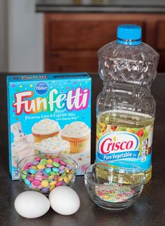 ingredients to make cupcakes including frosting, eggs and candy on a table