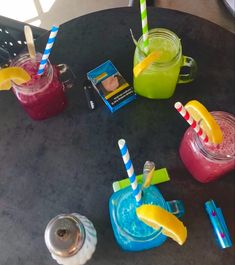 three cups with straws and two different colored drinks in them on a black table