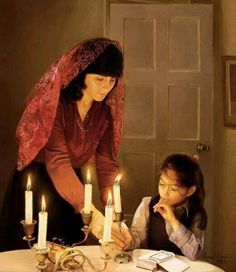 a woman and child sitting at a table with candles