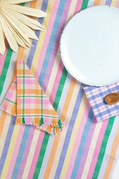 a plate and napkins on a striped table cloth with palm leaves in the background