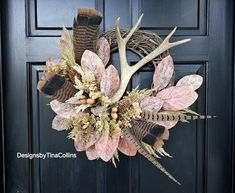 a wreath with antlers, leaves and berries hanging on the front door for fall