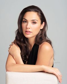 a woman with her arms crossed and looking at the camera while wearing a black top