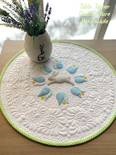 there is a vase with flowers and birds on the placemat in front of a window